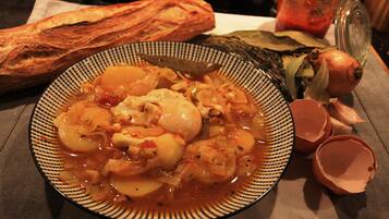 A plate of soup with vegetables and a baguette on a table.