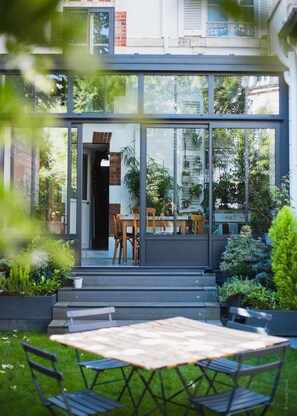 A modern house with a glass front, a wooden dining table, and chairs outside. - La Villa Dunois (Orléans)