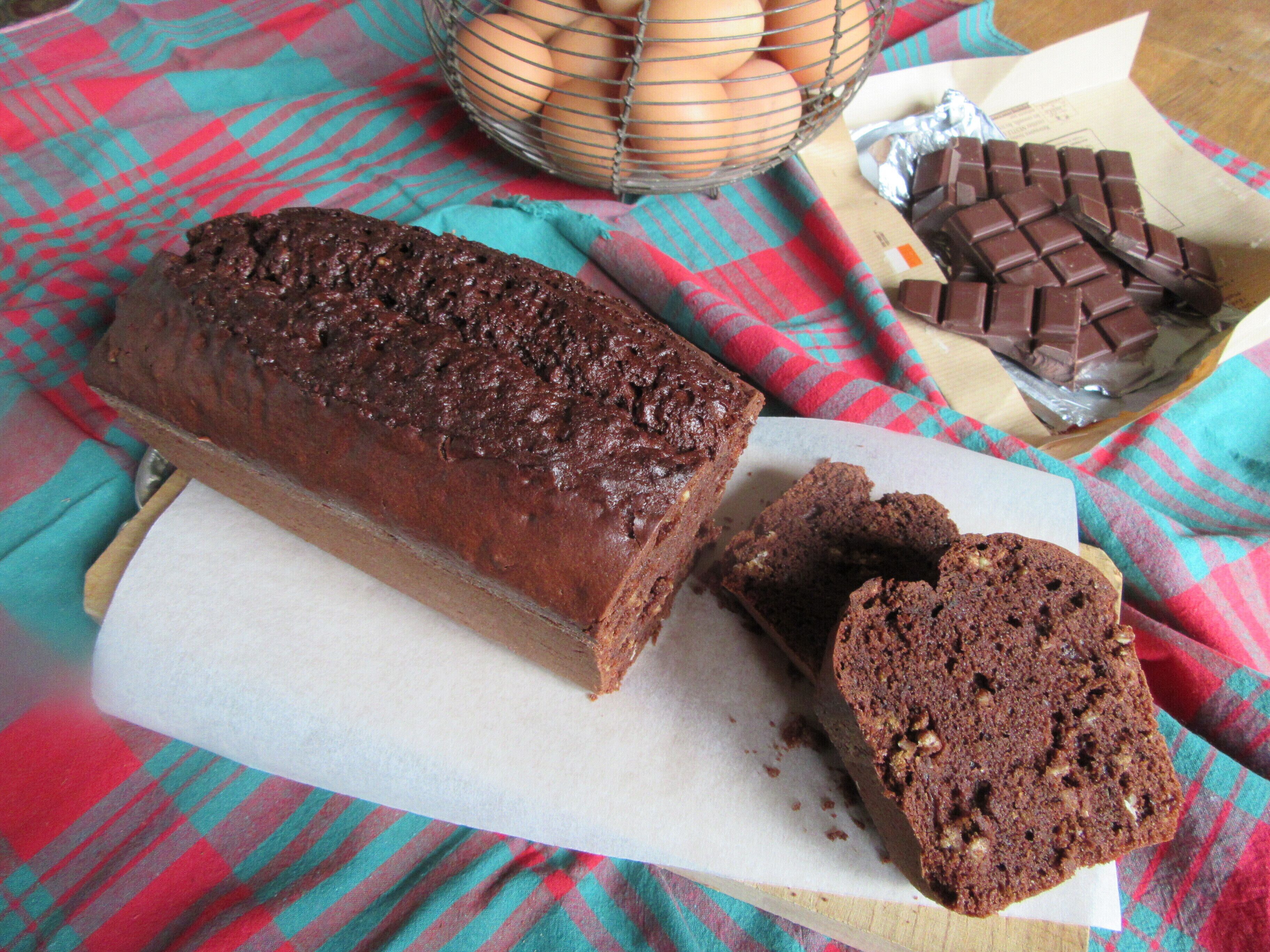 A loaf of chocolate bread on a cutting board with a checkered cloth underneath.