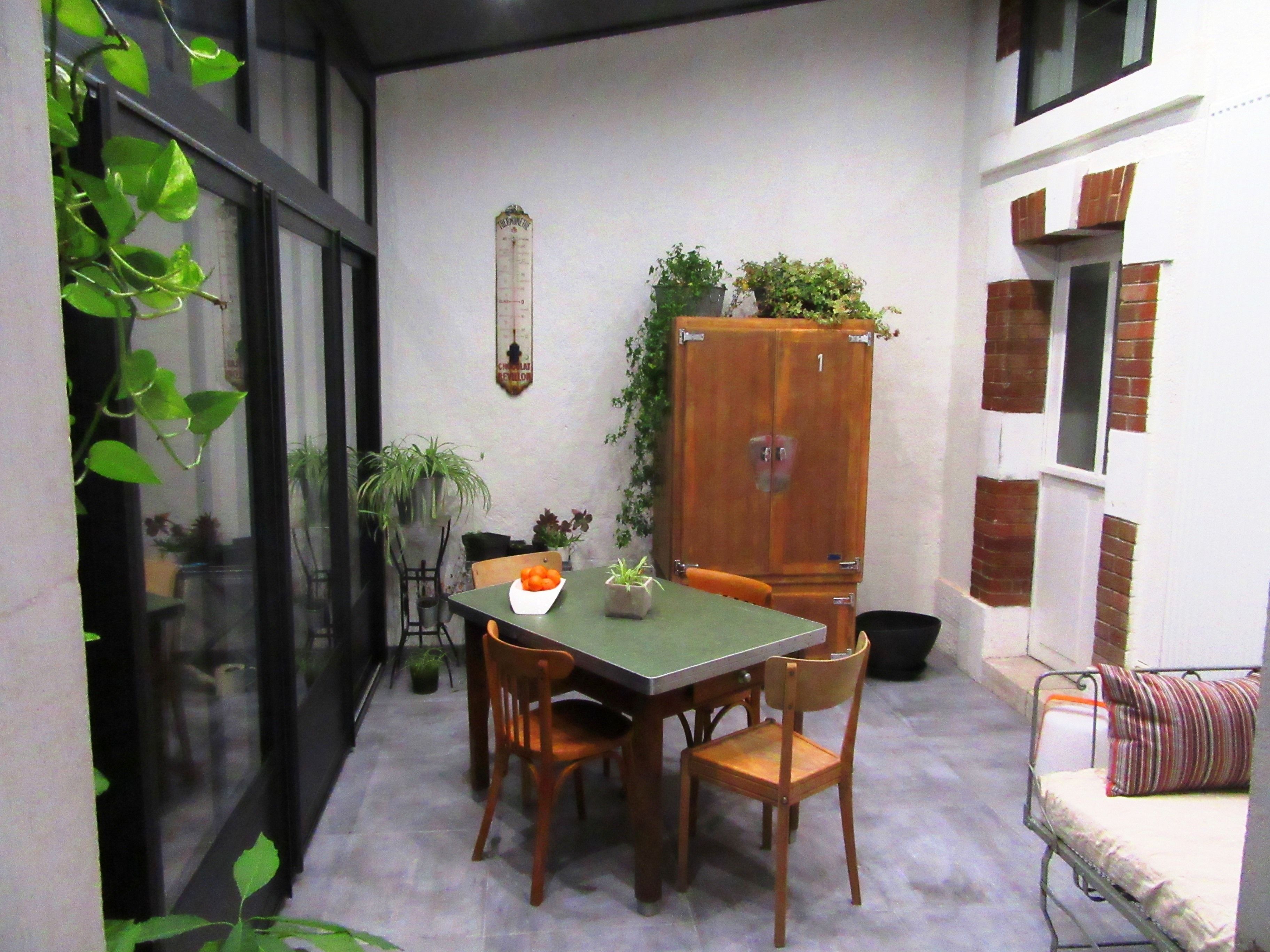 Un pequeño comedor con una mesa y sillas, un mueble con plantas y una ventana con vistas al exterior.