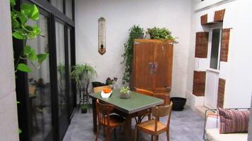 Un pequeño comedor con una mesa y sillas, un mueble con plantas y una ventana con vistas al exterior.