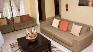 A living room with two sofas, a coffee table, and a painting on the wall. - Jayliz Lodge (Accra)