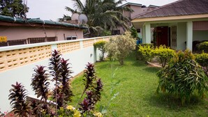 A residential house with a well-maintained lawn, a variety of plants, and a satellite dish on the roof. - Jayliz Lodge (Accra)