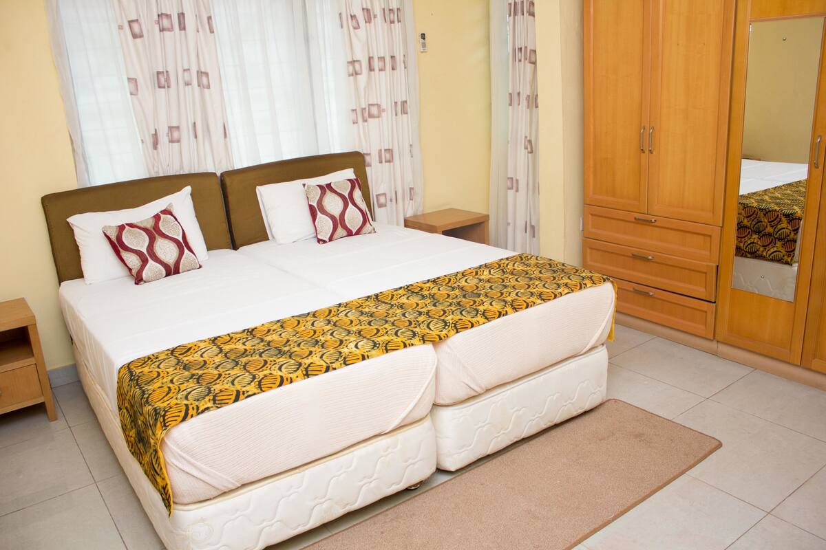 A bedroom with a double bed, two bedside tables, a wardrobe, and a mirror.