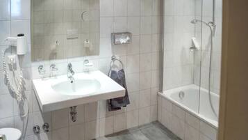 A modern bathroom with a white sink, mirror, and shower.