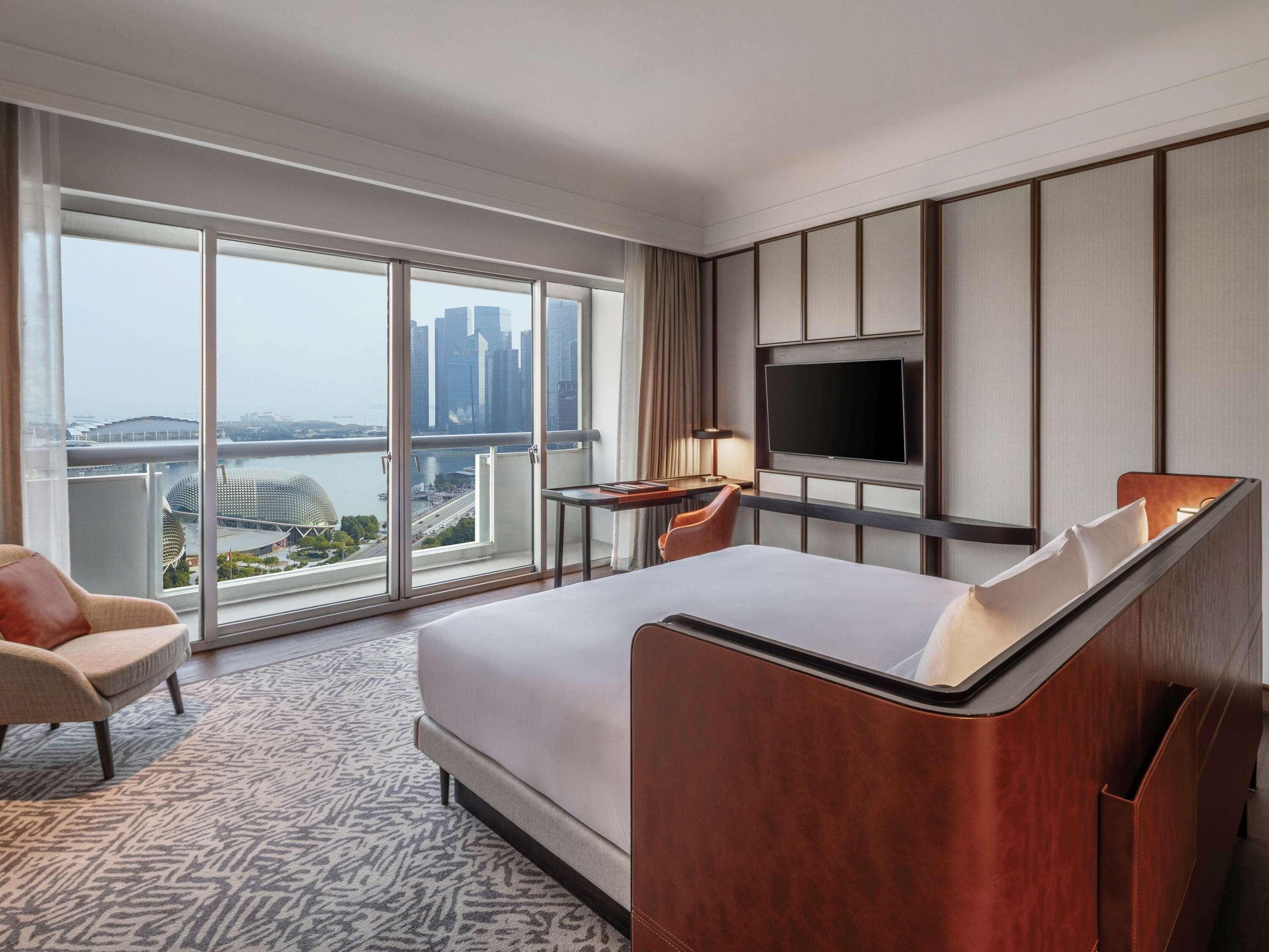 A hotel room with a large bed, a TV, a desk, and a chair.