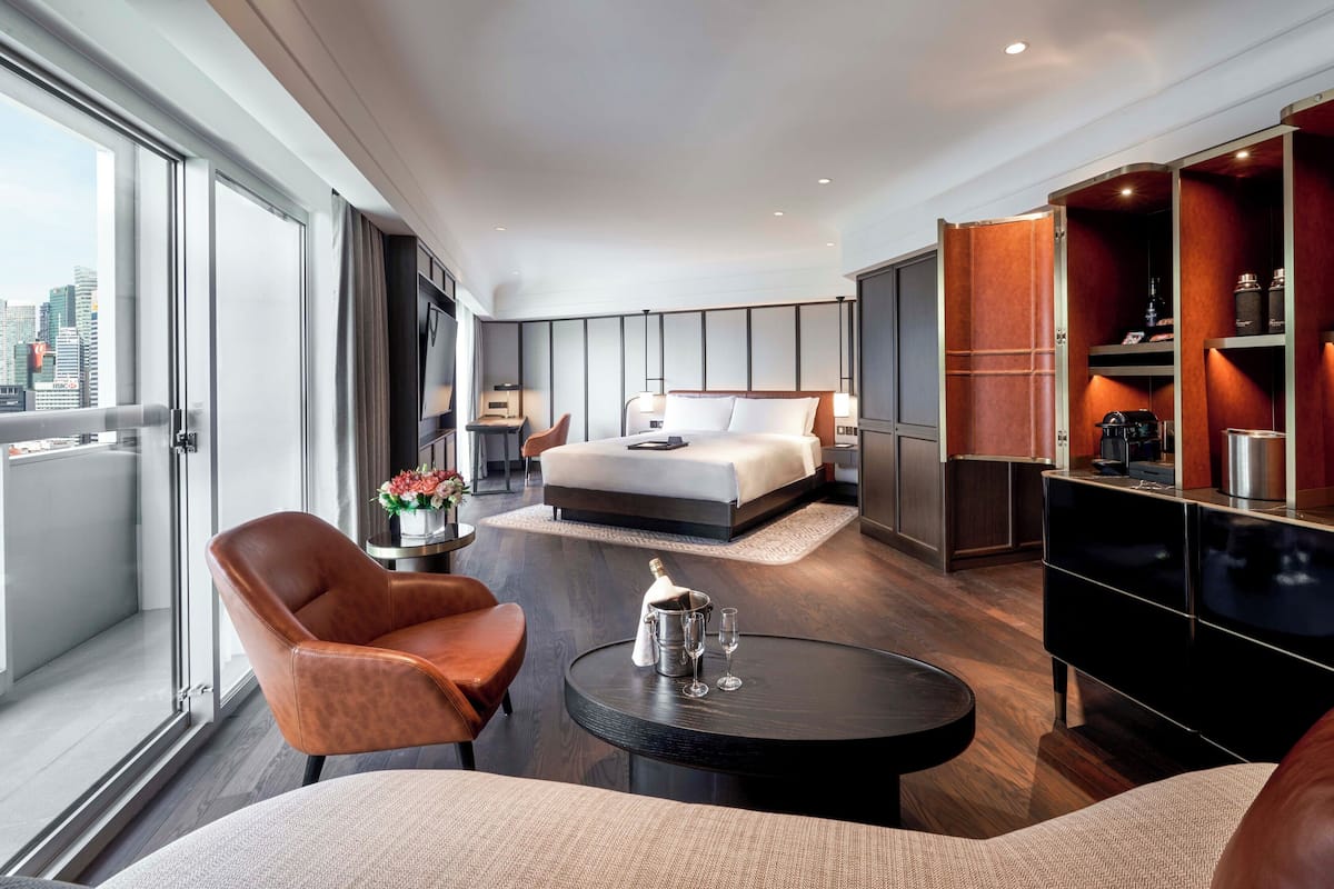 Een moderne hotelkamer met een groot bed, een zithoek met een salontafel en een kitchenette.
