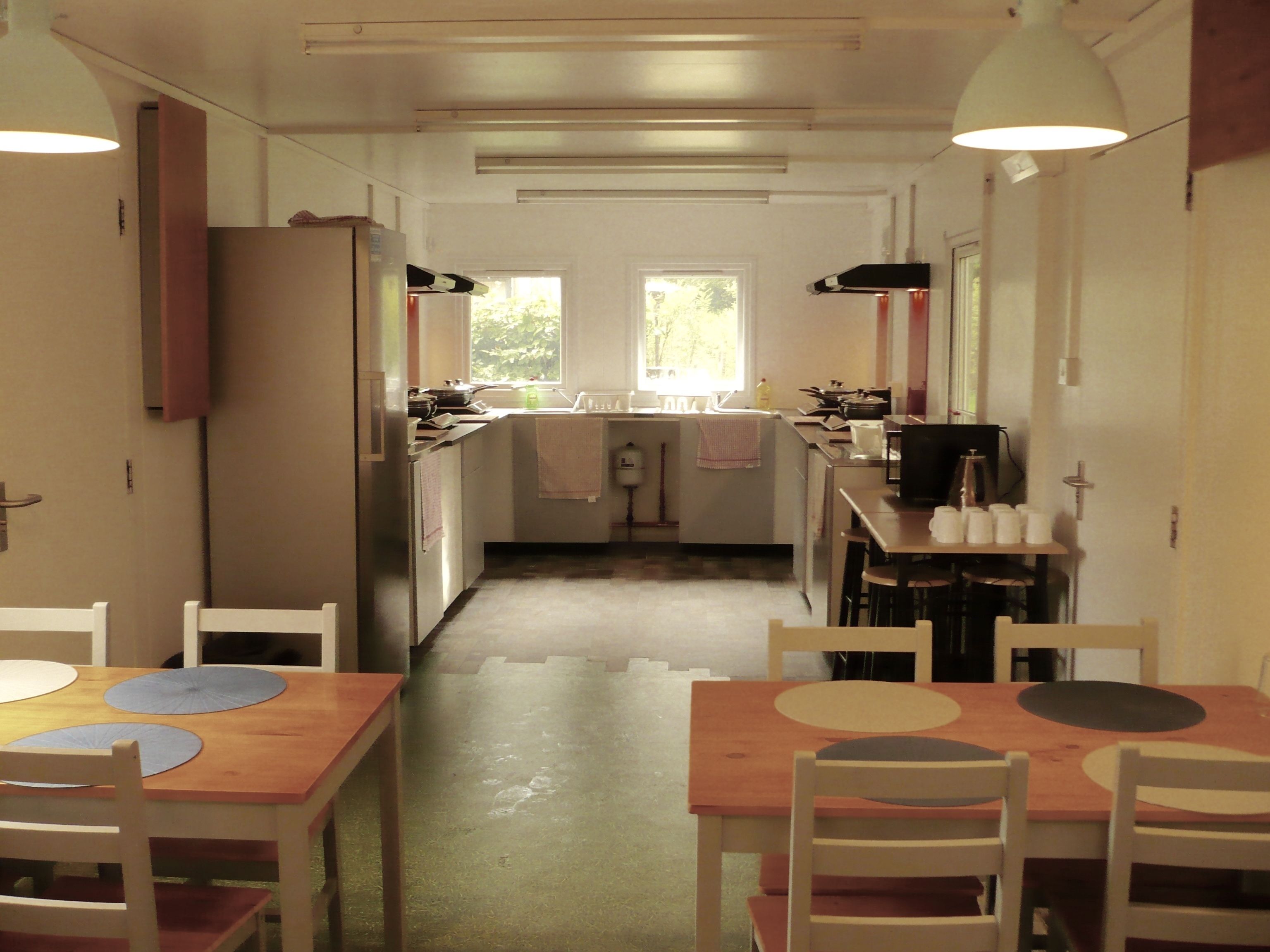 A narrow kitchen with a central island, white cabinets, and a window providing natural light.