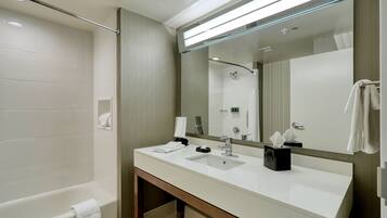 A modern bathroom with a bathtub, a large mirror, and a vanity with a sink.