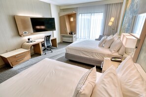 A hotel room with two beds, a desk, a TV, and a large window with curtains. - Courtyard by Marriott Southington (Southington)