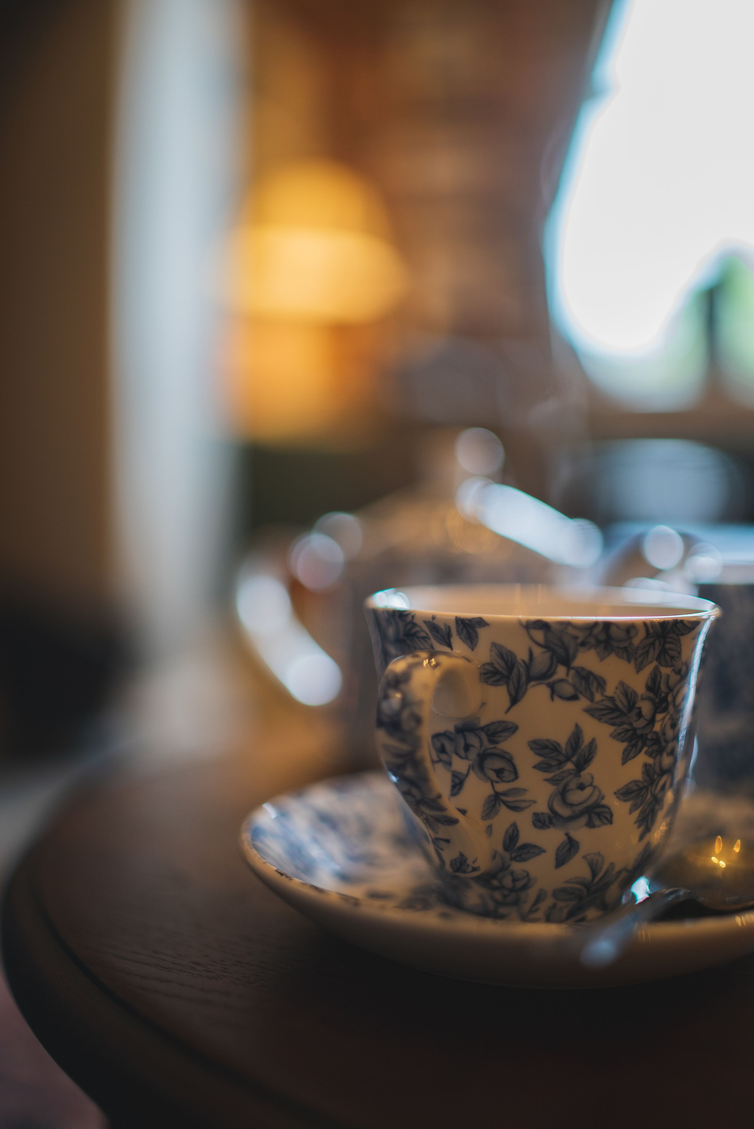 A cup with a floral pattern on a saucer, placed on a wooden table.