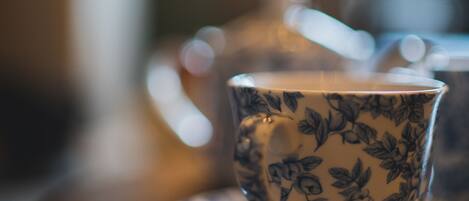 A cup with a floral pattern on a saucer, placed on a wooden table.