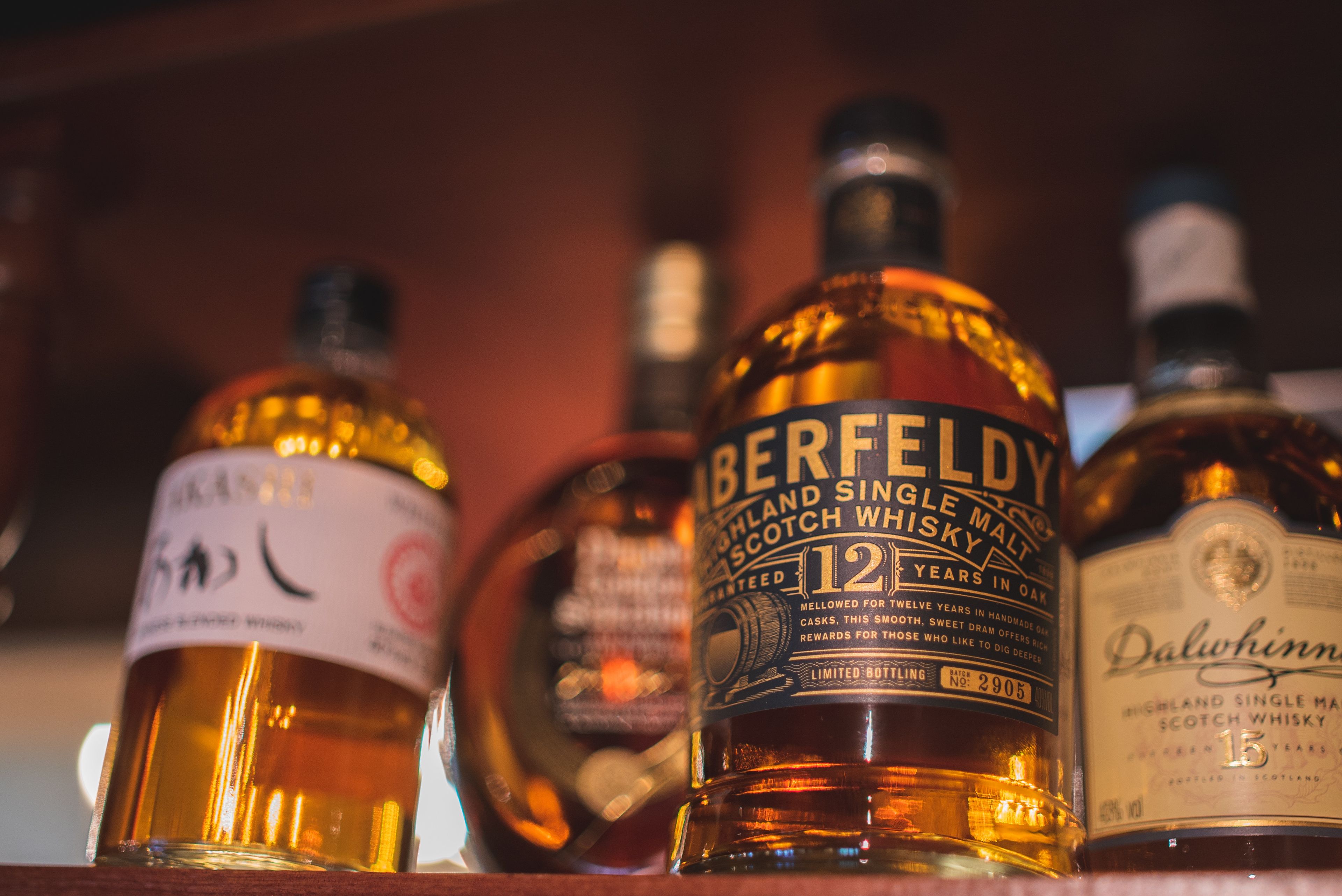 Een aantal whiskyflessen op een plank.