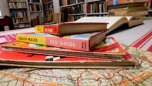 A collection of books and maps on a table in a library setting. - Cuffern Manor (Haverfordwest)