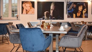 Un comedor con una mesa dispuesta para dos personas, sillas azules y obras de arte en la pared.