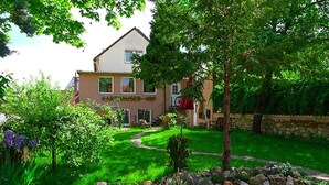 Una casa con un jardín cuidado, un pequeño estanque y un muro de piedra.