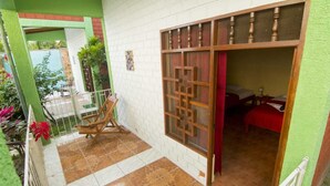 A room with a bed, a window with a decorative screen, a small table, and a chair.