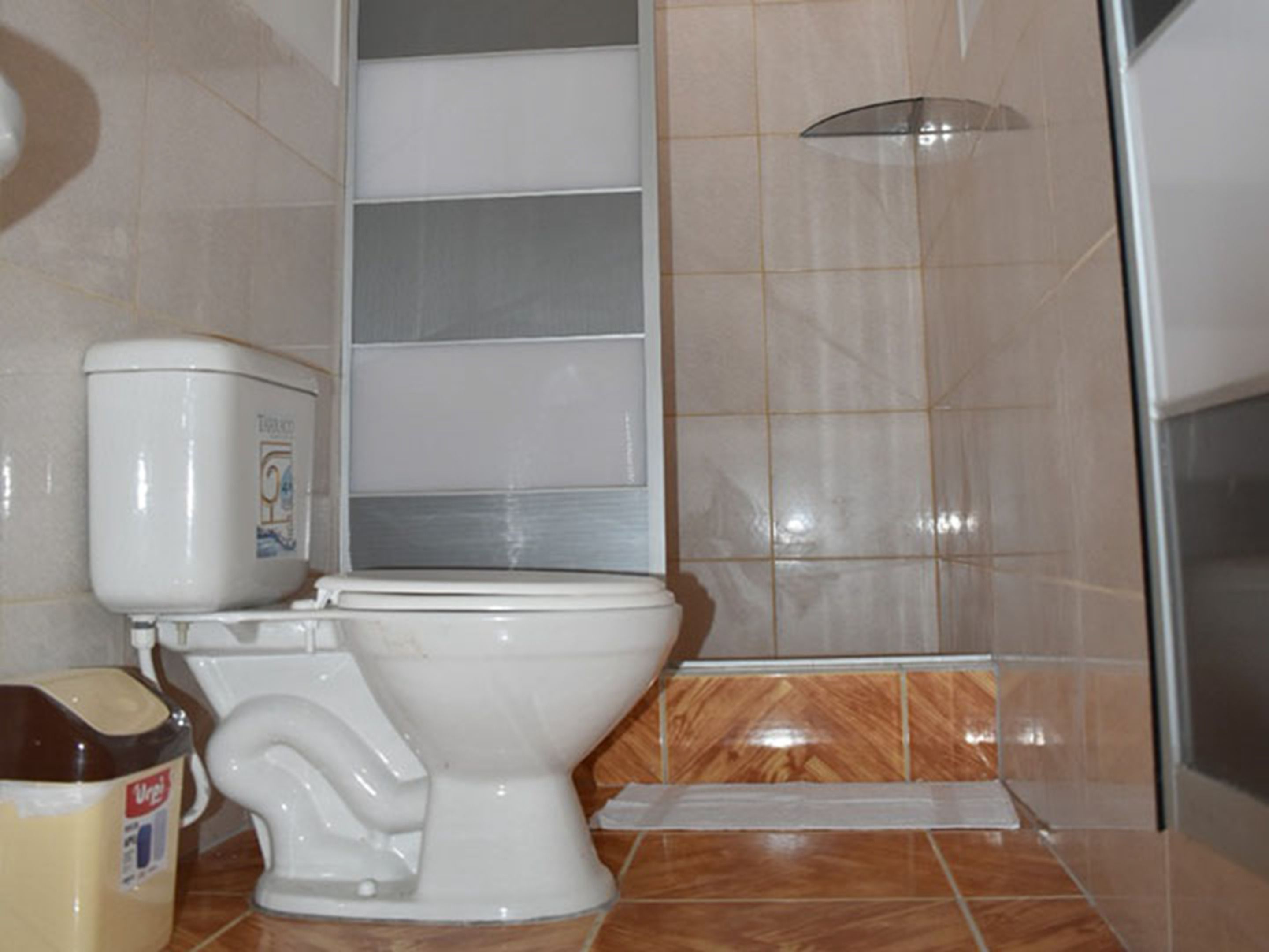 A bathroom with a toilet, a shower, and a tiled floor.