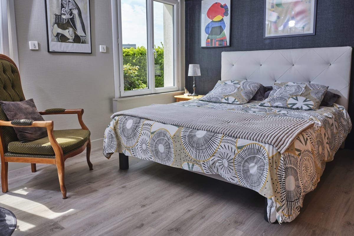 A bedroom with a bed, a chair, and artwork on the walls.