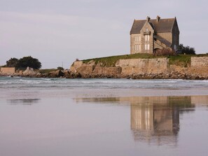 Un bâtiment en pierre doté d’un toit à forte pente, situé près d’une côte rocheuse.