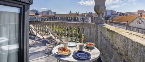 Een balkon met een ontbijttafel, met uitzicht op een stadsbeeld met historische gebouwen.