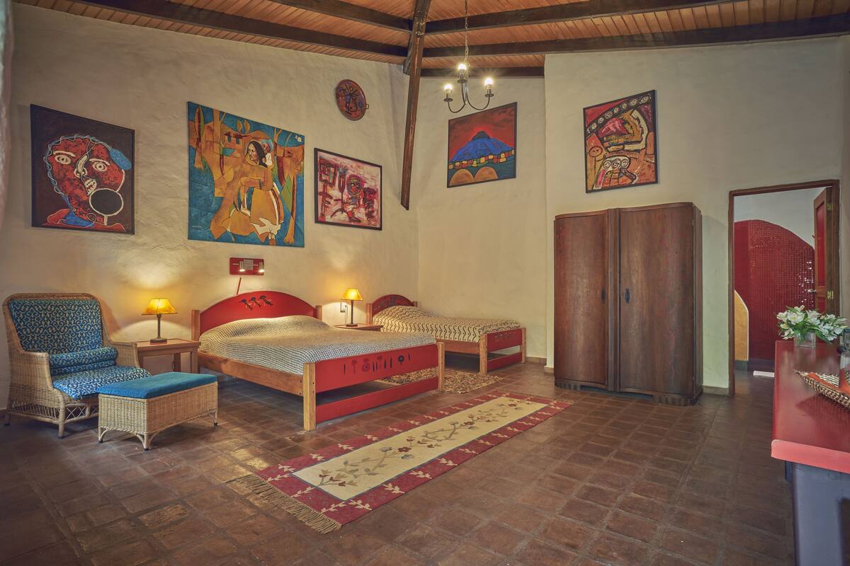 Een kamer met twee bedden, een stoel, een kledingkast en kunstwerken aan de muur.