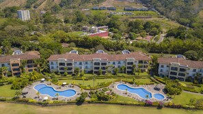 A resort with multiple buildings, a central swimming pool, and landscaped gardens.