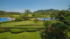 Ein Golfplatz mit zwei Schwimmbecken, üppiger Vegetation und einer Bergkulisse.
