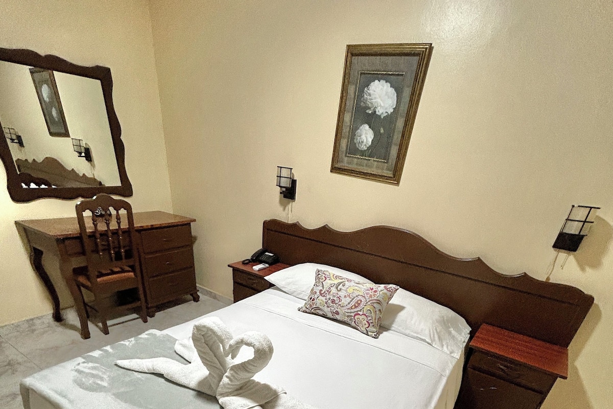 A neatly made bed with a white comforter and a towel.