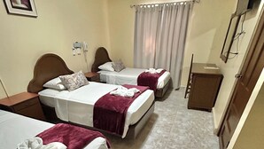 A hotel room with two beds, a small desk, a mirror, and a television. - Hotel Madrid Chiriqui (David)