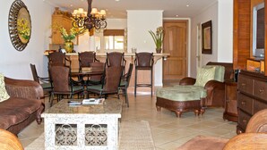 A spacious living room with a dining area, a kitchen in the background, and a wooden door leading to another room. - Los Suenos Resort Del Mar 3N (Jacó)