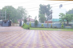 A paved courtyard with a patterned floor, surrounded by greenery and buildings. - Hotel Highland Resort (Mawal)