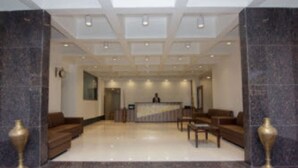 A lobby with a reception desk, seating area, and marble columns. - Hotel Highland Resort (Mawal)