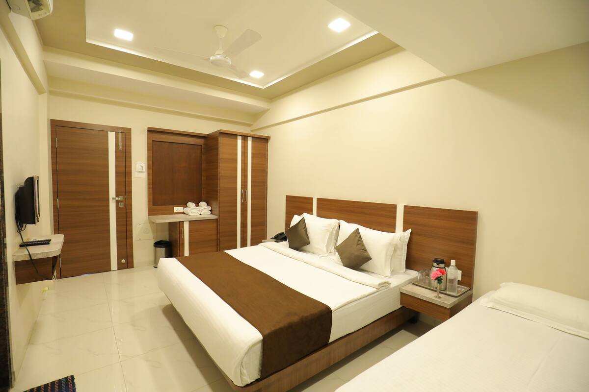 A hotel room with a large bed, a bedside table with a lamp, a wardrobe, and a ceiling fan.