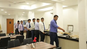 A conference room with a buffet setup, tables with chairs, and a ceiling fan. - Hotel Highland Resort (Mawal)