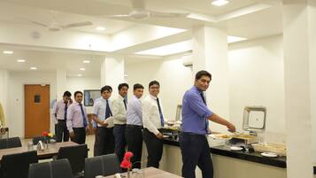 A conference room with a buffet setup, tables with chairs, and a ceiling fan.