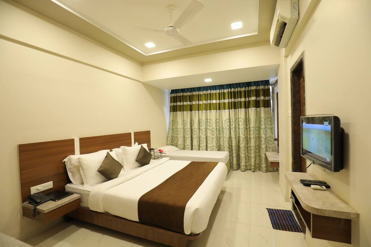 A hotel room with a large bed, a TV, a desk, and a ceiling fan.