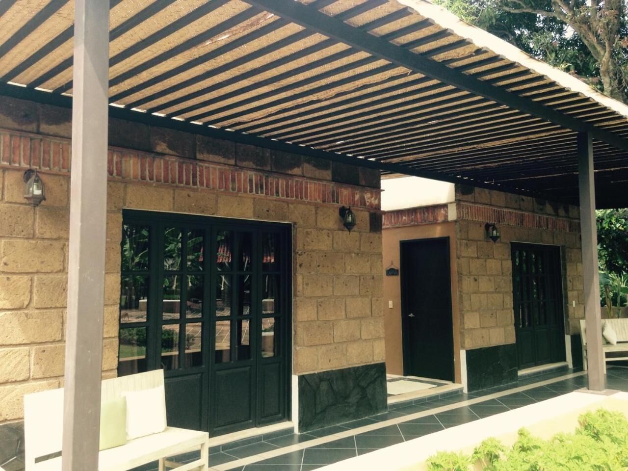 A covered outdoor area with a brick wall, two doors, and a bench.