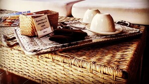 Una mesa de mimbre con una bandeja que sostiene un menú, un par de gafas de sol y dos tazas blancas.