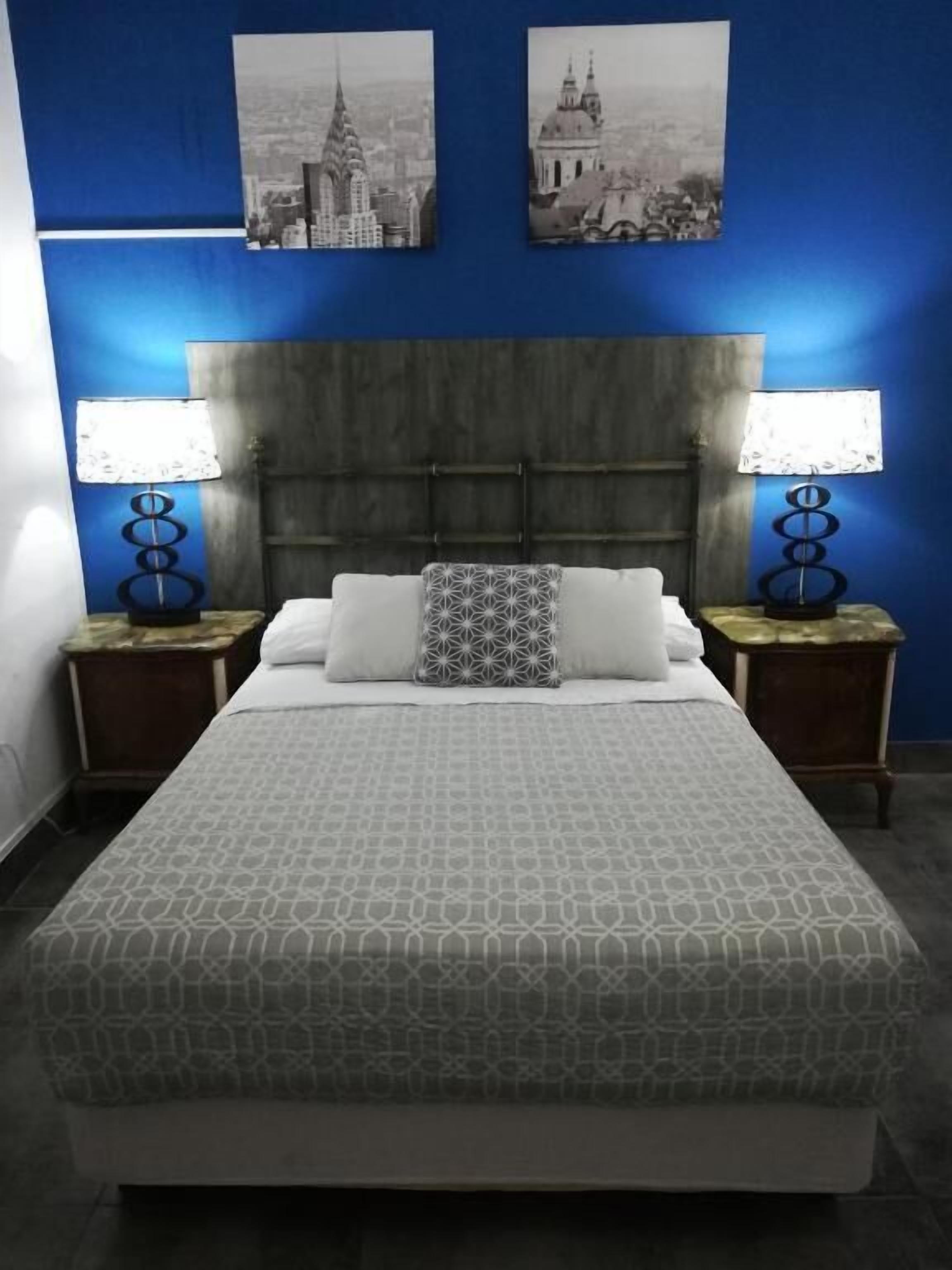 A hotel room with a large bed, two bedside tables with lamps, and two wall-mounted pictures.