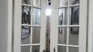 Un pasillo con una puerta blanca que presenta un diseño de entramado y un pequeño ventanal.