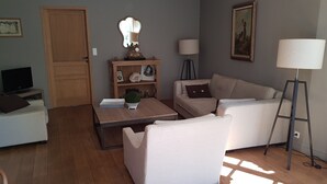 A living room with a sofa, a coffee table, a TV, a bookshelf, and a lamp.