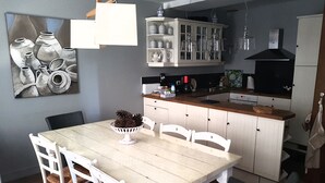 A kitchen with white cabinets, a wooden countertop, and a dining area with a table and chairs.