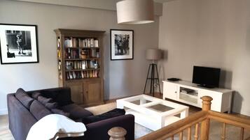 Relax in this stylish living room with a sofa, coffee table, bookshelf, and flat-screen TV.
