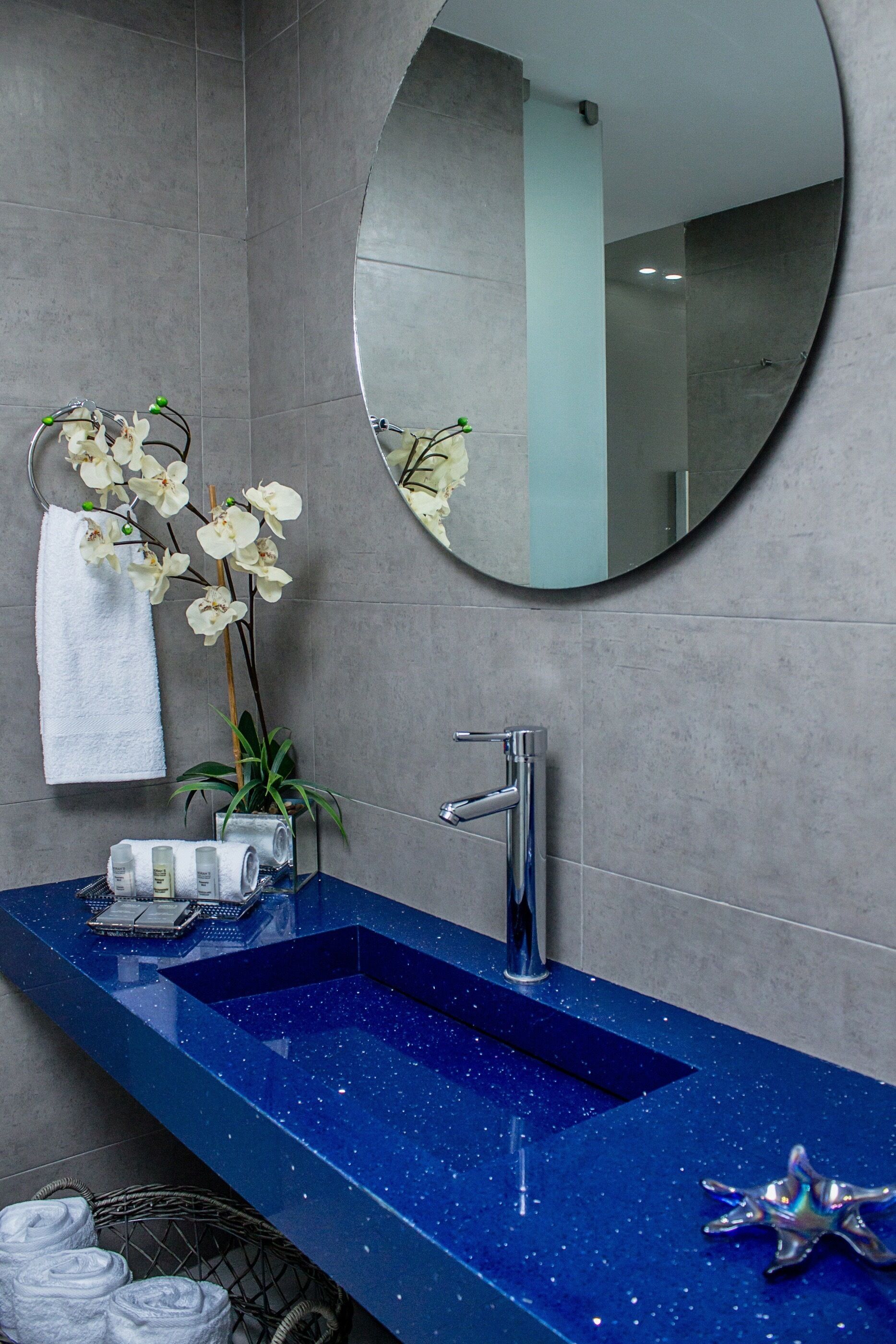 Un baño con un lavabo azul, un espejo y un perchero para toallas.