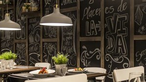 A restaurant interior with blackboard walls, white chairs, and pendant lighting. - LD Plus (Paraguachí)