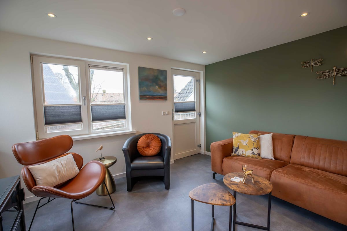 A modern living room with a brown leather sofa, a brown leather armchair, and a small round table.