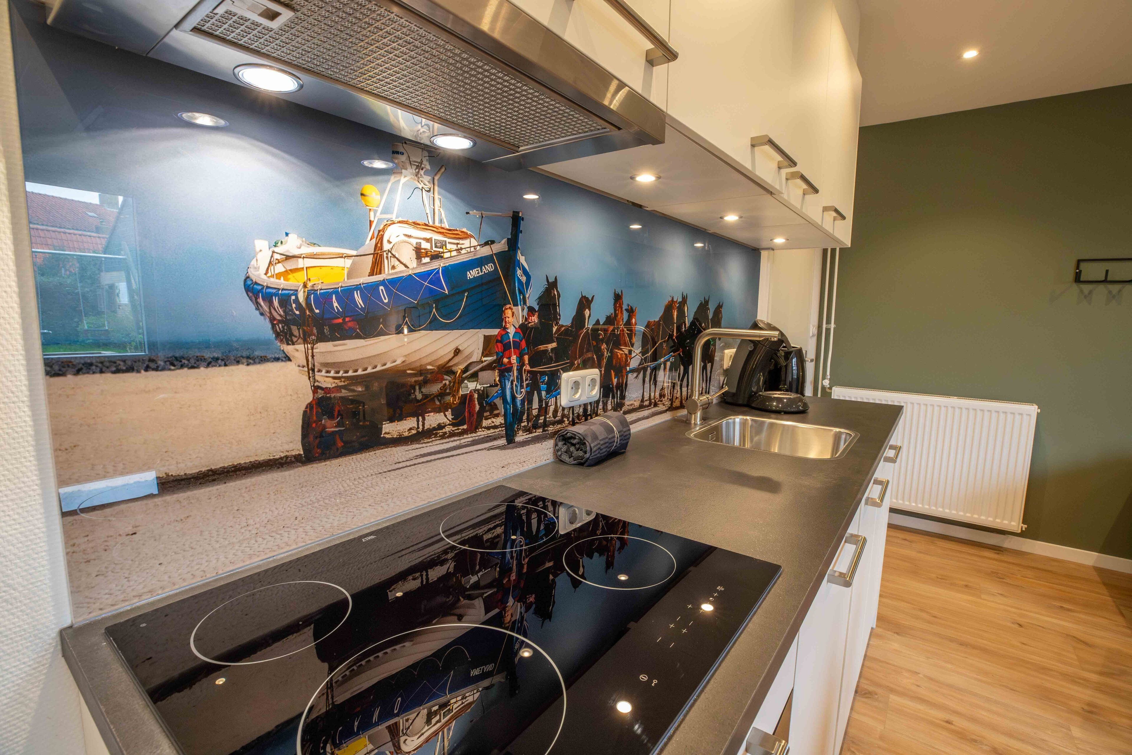 A modern kitchen with a central island, a built-in stove, and a backsplash depicting a maritime scene.