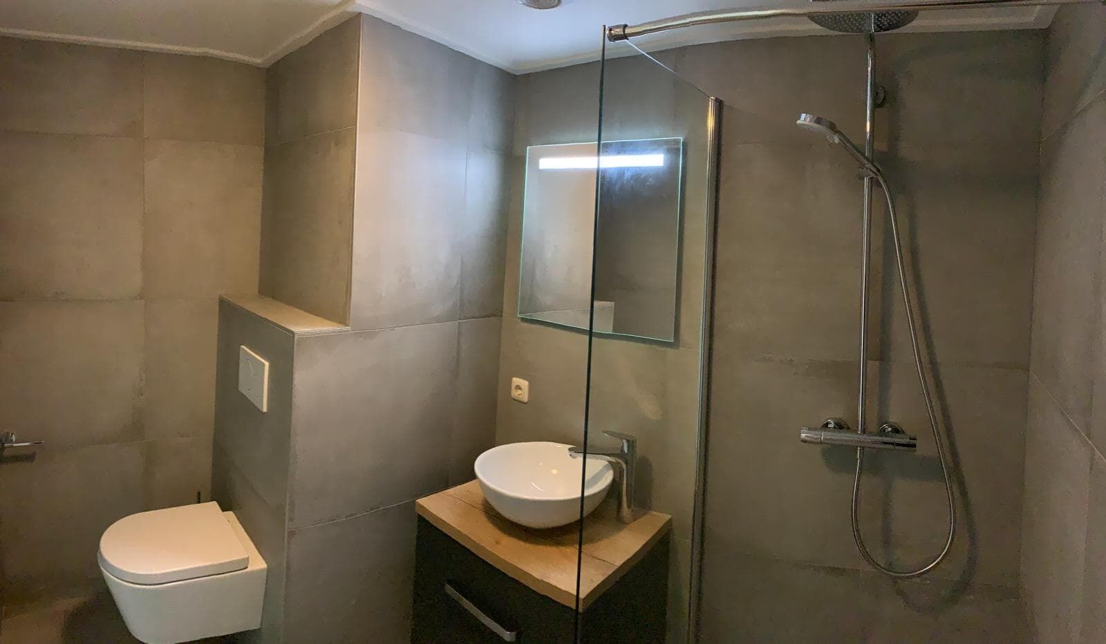 Un baño moderno con inodoro, lavamanos y ducha.