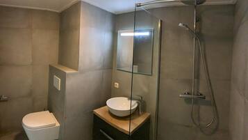 Un baño moderno con inodoro, lavamanos y ducha.